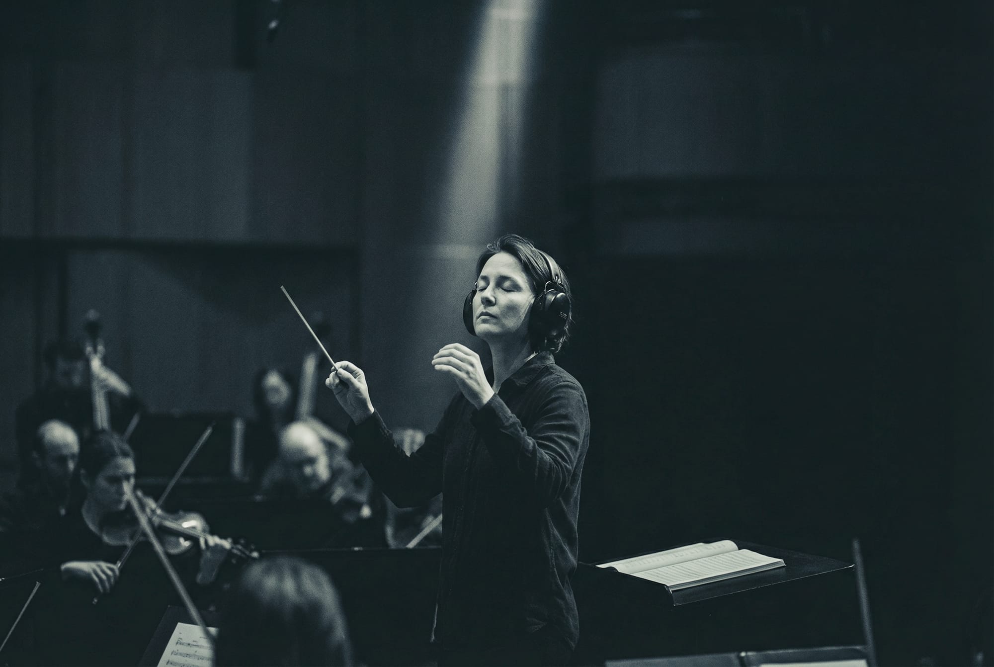 Conductor with closed eyes, orchestra blurred behind